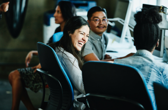 Three co-workers sitting in an office setting, smiling